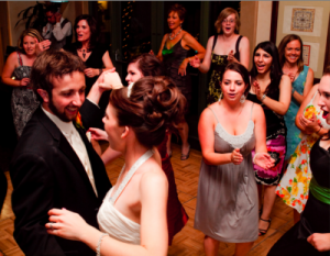 Ally and Anthony, bride and groom, dance surrounded by happy guests.