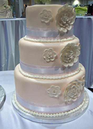 cream wedding cake with flowers and white ribbon