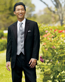 Man in black pinstripe tuxedo, unbuttoned, with gray vest and tie