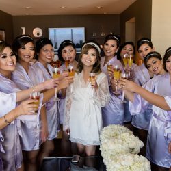 Bride Erica and her bridesmaids wearing fun satin robes and drinking champagne