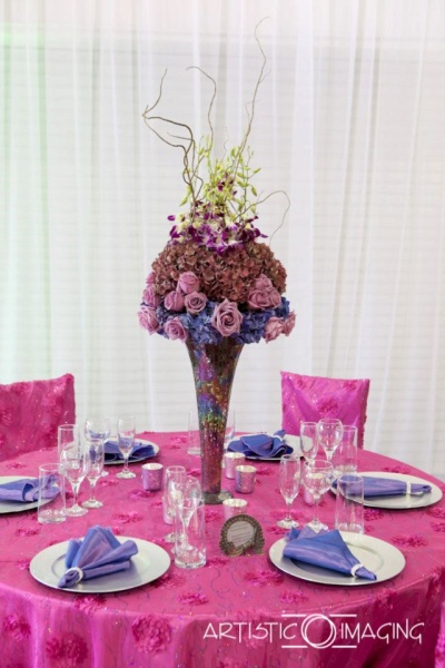 reception table with pink linens, silver plates, purple napkins, tall centerpiece