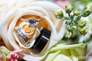 wedding rings atop a cream rose